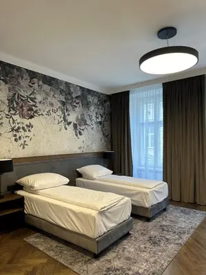 a bedroom with two beds and a large window at Dom Gościnny Uniwersytetu Jagiellońskiego in Kraków