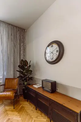 a living room with a table and a clock on the wall at Rzeszowska 5 Apt 7 Stylowy pobyt in Kraków
