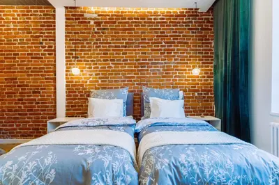 two beds sitting next to a brick wall at Rzeszowska 5 Apt 12 Stylowy pobyt in Kraków