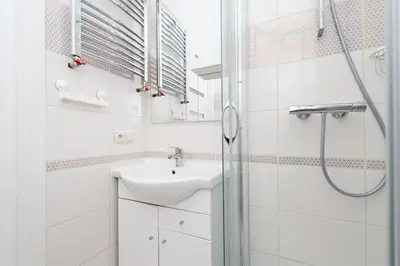 a white bathroom with a sink and a shower at Dietla Old Town, Sun & Snow in Kraków