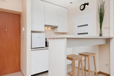 a kitchen with white cabinets and a table and two stools at Dietla Old Town, Sun & Snow in Kraków