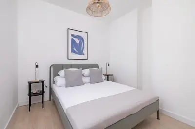 a bedroom with a bed with white sheets and a chandelier at Studio apartment - Starowiślna 69 street in Kraków