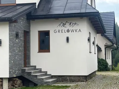 a white building with a sign on the side of it at Grelówka Apartament in PyzÃ³wka