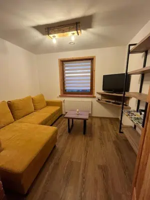 a living room with a couch and a table at Grelówka Apartament in PyzÃ³wka