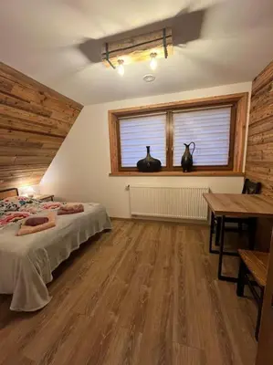 a bedroom with a bed and a window and a table at Grelówka Apartament in PyzÃ³wka
