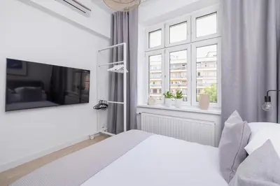 a white bedroom with a bed and a window at 2-bedroom apartment - Starowiślna 69 street in Kraków