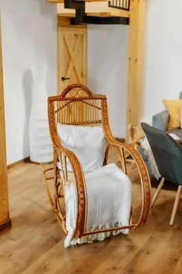 a rattan chair with a white seat in a living room at JÓZEFÓWKA Stara Stodoła in Zagórze
