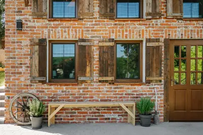a brick building with a bench and two windows at JÓZEFÓWKA Stara Stodoła in Zagórze