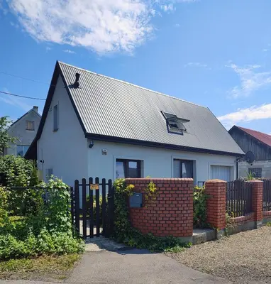 a white house with a metal roof and a brick fence at Dom na wsi w okolicy ENERGYLANDIA ZATOR in Łączany