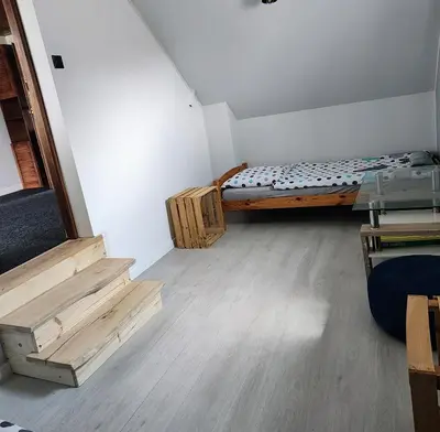 a room with a bed and wooden stairs in it at Dom na wsi w okolicy ENERGYLANDIA ZATOR in Łączany