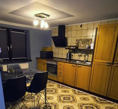 a kitchen with wooden cabinets and a table and chairs at Dom na wsi w okolicy ENERGYLANDIA ZATOR in Łączany