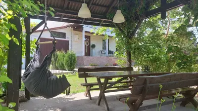 a hammock hanging from a pergola with a table and benches at Cottage Zawoja z Jacuzzi in Zawoja
