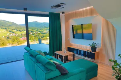 a dining room with a table and chairs and a large window at Beskid Island in Dobra
