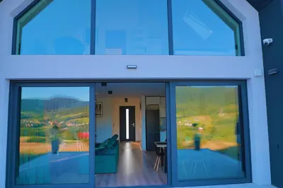 a living room with a green couch and a large window at Beskid Island in Dobra