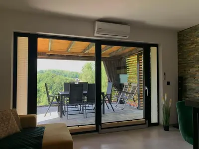 a living room with sliding glass doors with a table and chairs at Domek Stróski in Wola Stróska