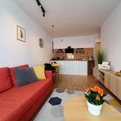 a kitchen with white cabinets and a brick wall at Nowa Huta - Stay Here in Kraków