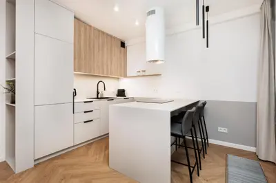 a kitchen with white cabinets and a counter with stools at Comfort Corner in Kraków - by Upstairs in Kraków
