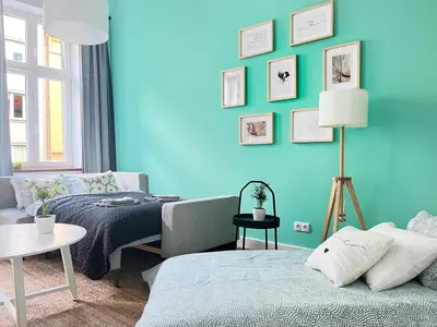a room with a blue wall with a bed and a couch at Beautiful Apartment for 8 people in Cracow's heart in Kraków
