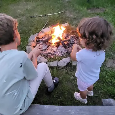 a man and a little girl sitting next to a fire at Domek drewniany z sauną in Bieńkówka