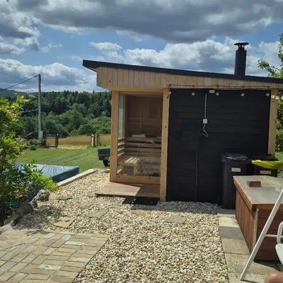 a small black shed sitting in a garden at Domek drewniany z sauną in Bieńkówka