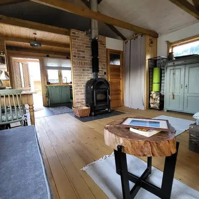 a living room with a wood stove and a table at Domek drewniany z sauną in Bieńkówka
