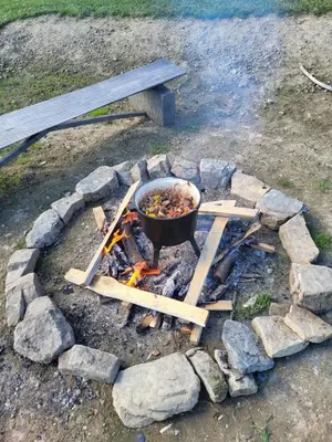 a pot on top of a fire pit with logs at Domek drewniany z sauną in Bieńkówka
