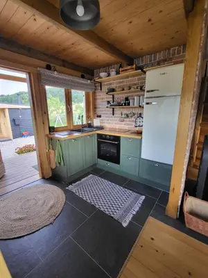 a kitchen with green cabinets and a white refrigerator at Domek drewniany z sauną in Bieńkówka