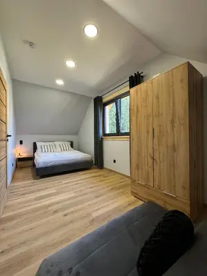a bedroom with a bed and a wooden floor at Domek DE-Luxe BUFLAK in Nowy Targ