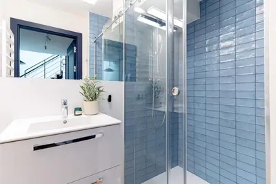 a bathroom with a sink and a shower with blue tiles at Miodova20 by StayLab in Kraków