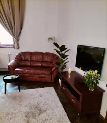 a living room with a brown leather couch and a television at ChilLoud - apartament na Kazimierzu in Kraków