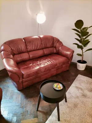 a brown leather couch in a living room with a table at ChilLoud - apartament na Kazimierzu in Kraków