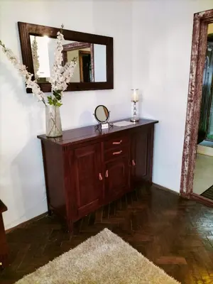 a dresser with a mirror and a vase with flowers on it at ChilLoud - apartament na Kazimierzu in Kraków