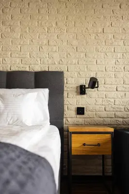 a bedroom with a bed and a nightstand next to a brick wall at Różana Loft - Old Town in Kraków