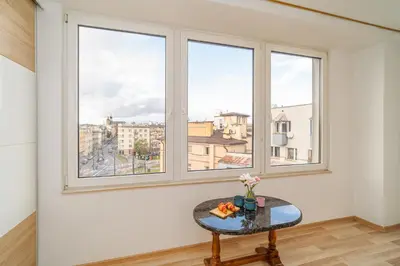 a room with three windows and a table with flowers at Penthouse in the Center - by Hosty in Kraków
