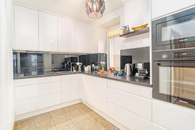 a white kitchen with white cabinets and appliances at Penthouse in the Center - by Hosty in Kraków