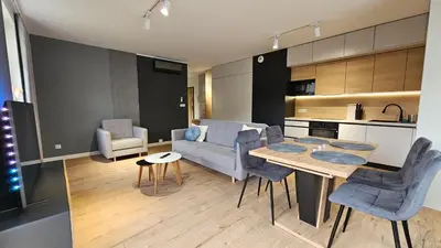 a kitchen and a living room with a table and chairs at Apartament Zdunów in Kraków