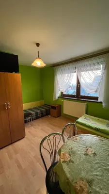 a green room with a table and chairs and a window at Noclegi u Basi in Klikuszowa