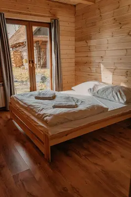 a large bed in a wooden room with a window at Sosnowy Domek Parter Zator Energylandia Graboszyce in Graboszyce