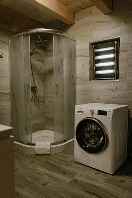 a washing machine in a bathroom with a shower at Sosnowy Domek Parter Zator Energylandia Graboszyce in Graboszyce