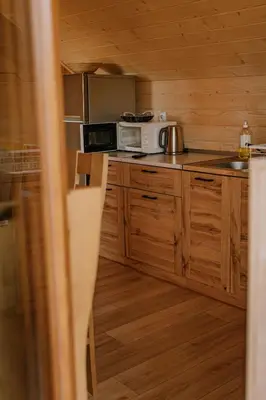 a kitchen with wooden cabinets and a microwave at Sosnowy Domek Parter Zator Energylandia Graboszyce in Graboszyce