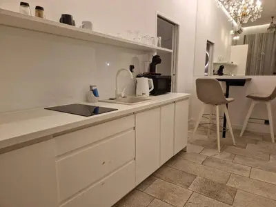 a white kitchen with a sink and a counter at Dodo Acomodo 6 in Kraków