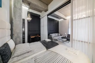 a bedroom with a large bed and a living room at Dodo Acomodo 6 in Kraków