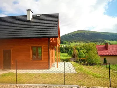 a wooden house with a black roof at Słoneczna Chata dom Kasina Wielka in Kasina Wielka