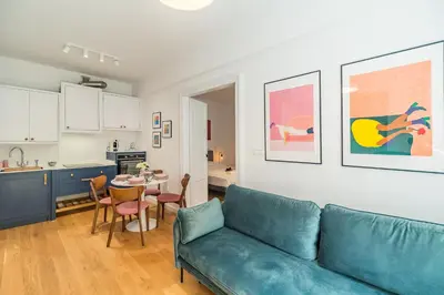 a living room with a blue couch and a kitchen at Kraków Wawel Apartment - Top Location, Workspace - by Rentujemy in Kraków