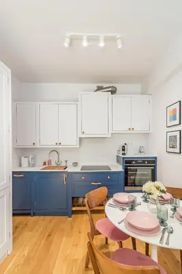 a kitchen with blue cabinets and a table with chairs at Kraków Wawel Apartment - Top Location, Workspace - by Rentujemy in Kraków
