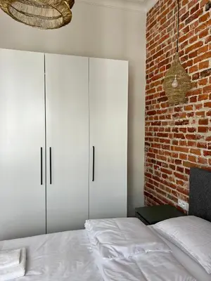 a bedroom with white cabinets and a brick wall at Sebastiana Street Luxury Apartment in Kraków