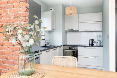 a kitchen with a brick wall and a vase with flowers at Krowodrza 2-Bedroom Apartment by BookingHost in Kraków