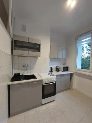a kitchen with white cabinets and a sink and a window at Apartament Aleja 29 Listopada in Kraków