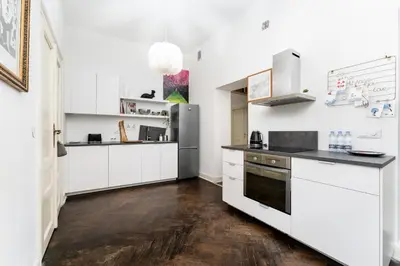 a kitchen with white cabinets and black counter tops at Old Town Spacious Apartment by BookingHost in Kraków