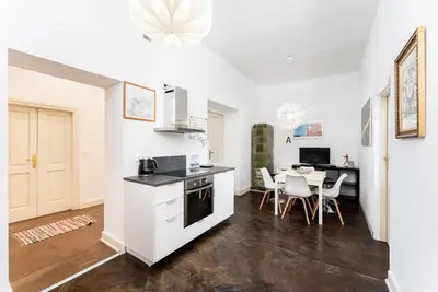 a kitchen with white cabinets and a table with chairs at Old Town Spacious Apartment by BookingHost in Kraków